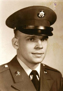 A young man in a military uniform and cap poses for a formal portrait, looking slightly to the side with a neutral expression. The photo is in sepia tone.